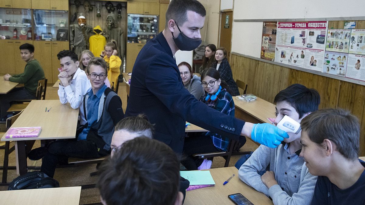 Преподаватель измеряет температуру ученику в московской школе.
