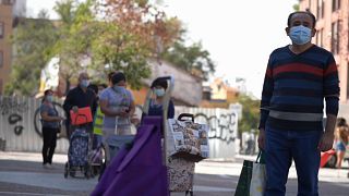 Residents wait in line at a foodbank in one of Spain's most impoverished districts. 