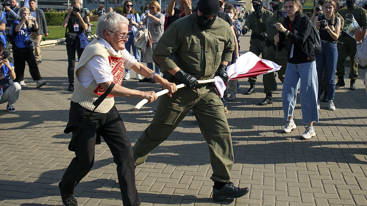 A police officer tries to take away an old Belarusian national flag from Nina Bahinskaya's hands during an opposition rally to protest the official election results.