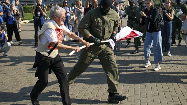 Un agente forcejea con Nina Baginskaya para quitarle la antigua bandera bielorrusa Un agente forcejea con Nina Baginskaya para quitarle la antigua bandera bielorrusa