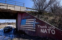 A car drives past a graffiti reading 'Thank You Nato' and featuring the US flag near the village of Stagovo on March 24, 2019.