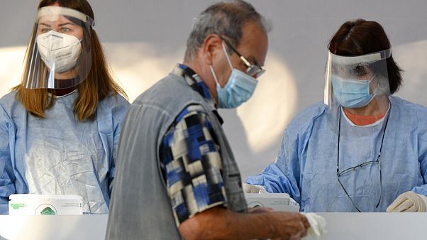 A man wearing a mask against the COVID-19 infection holds gloves he received after having his temperature tested before being allowed into a voting station in Bucharest. A man wearing a mask against the COVID-19 infection holds gloves he received after having his temperature tested before being allowed into a voting station in Bucharest.