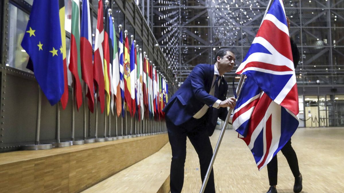 Un membre du protocole retire le drapeau du Royaume-Uni du bâtiment Europa à Bruxelles, le 31 janvier 2020, alors qu'il a mis fin à ses 47 ans d'appartenance à l'UE.