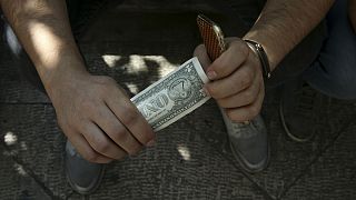 An Iranian street money exchanger holds a U.S. banknote in downtown Tehran, Iran