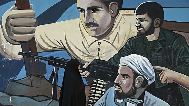 A woman walks past of a mural depicting members of Iran's Basij volunteer paramilitary force, in downtown Tehran, Iran A woman walks past of a mural depicting members of Iran's Basij volunteer paramilitary force, in downtown Tehran, Iran