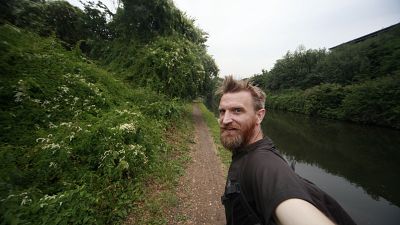 Guerrilla geographer, Daniel Raven-Ellison walking along the side of a canal Guerrilla geographer, Daniel Raven-Ellison walking along the side of a canal