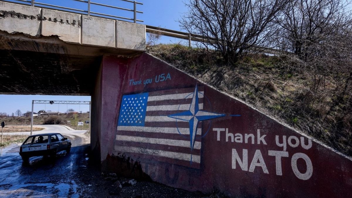 Un coche pasa por delante de un graffiti que dice "Thank You Nato" y que muestra la bandera estadounidense cerca del pueblo de Stagovo el 24 de marzo de 2019.