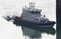 A Border Force vessel brings a group of people thought to be migrants into the port city of Dover, England, from small boats, Saturday Aug. 8, 2020.