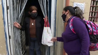 Una voluntaria entrega ayuda alimentaria a una mujer en Buenos Aires