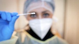 Medizinisches Personal zeigt ein Wattestäbchen für einen Rachen-Abstrich zum Corona-Test