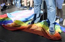 رجل يقف على علم قوس قزح خلال مظاهرة ضد المثليين والمتحولين جنسيا