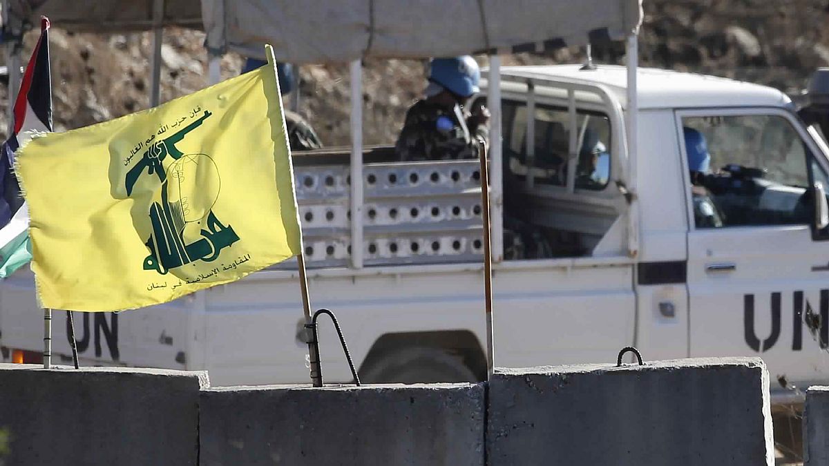 دورية تابعة للأمم المتحدة تمر بجانب علم حزب الله وحاجز إسمنتي في جنوب لبنان على الحدود مع إسرائيل