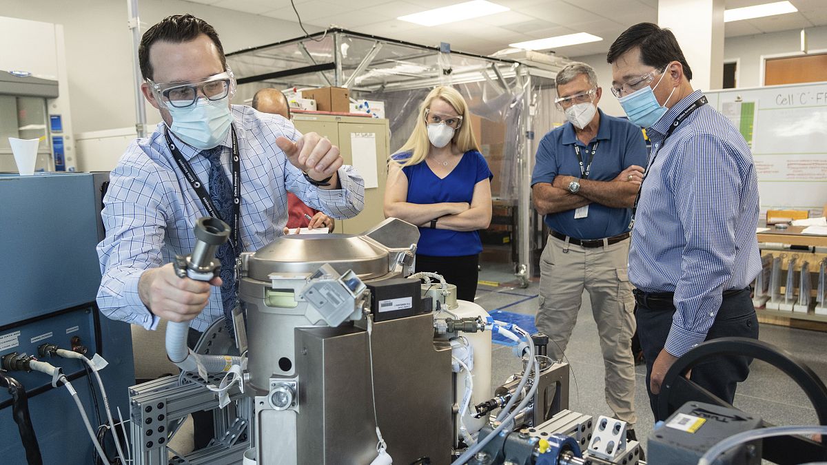 In this June 18, 2020 photo provided by NASA, astronaut Kate Rubins, center, and support personnel review the Universal Waste Management System, a low-gravity space toilet.