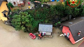 Firefighters evacuate people from a house amidst flooding in the town of Ornavasso