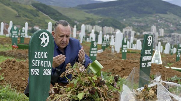 Tarik Svraka visits the graves of his parents in law who died of COVID-19 related complications, in Zenica, Bosnia, Monday, Sept. 28, 2020. Tarik Svraka visits the graves of his parents in law who died of COVID-19 related complications, in Zenica, Bosnia, Monday, Sept. 28, 2020.