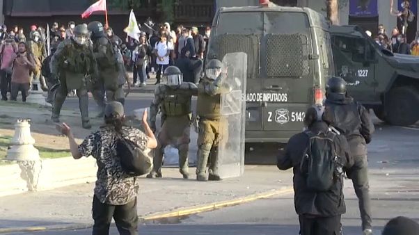 Carabineros se protegen con sus escudos durante la protesta en Santiago Carabineros se protegen con sus escudos durante la protesta en Santiago
