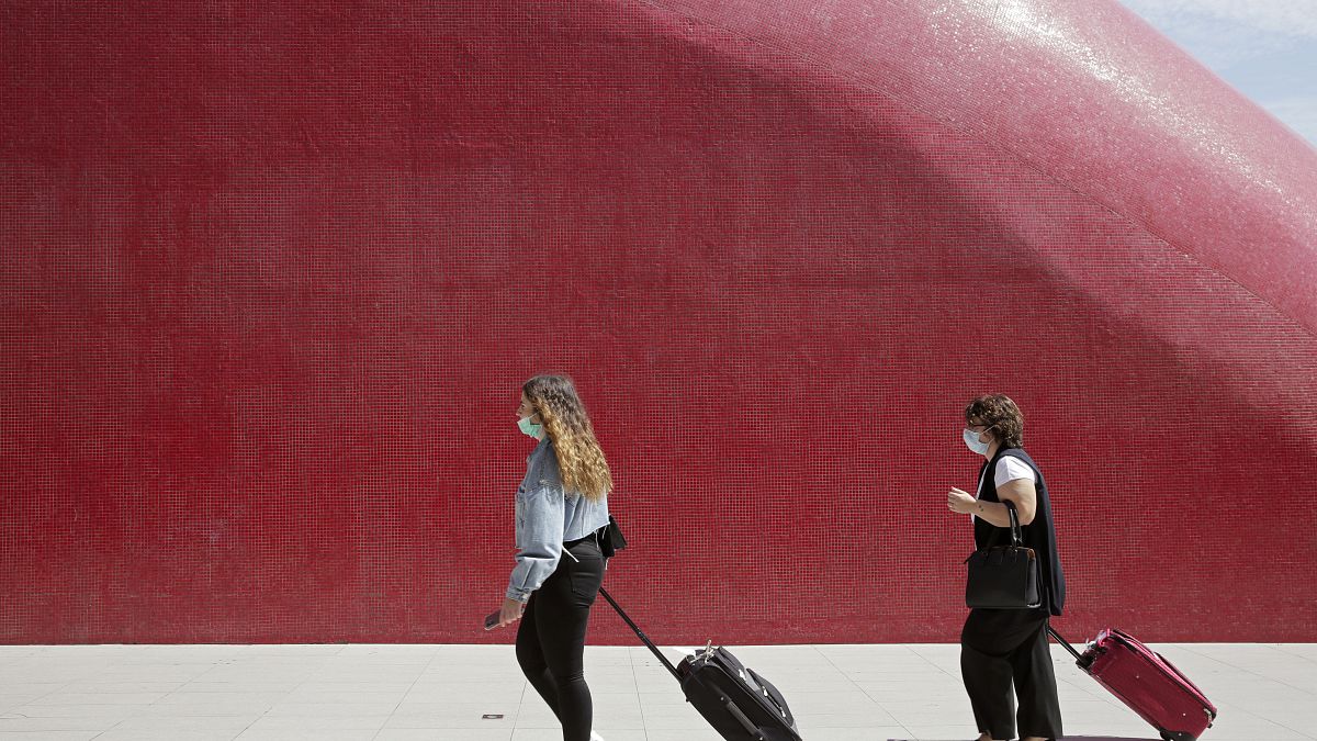 Two women wearing face masks pull their suitcases outside Lisbon's airport, Friday, Sept. 11, 2020