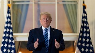 El Presidente Donald Trump saluda en el Balcón del Salón Azul al regresar a la Casa Blanca el lunes 5 de octubre de 2020, en Washington.