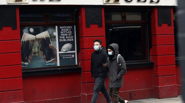 Menschen mit Gesichtsmasken vor einem Pub in Dublin, 16.03.2020 Menschen mit Gesichtsmasken vor einem Pub in Dublin, 16.03.2020