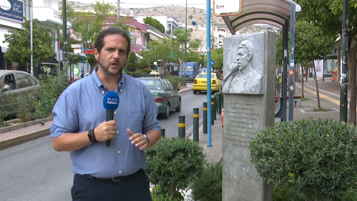 Корреспондент Панос Кицикопулос у памятника убитому музыканту-антифашисту в Афинах.