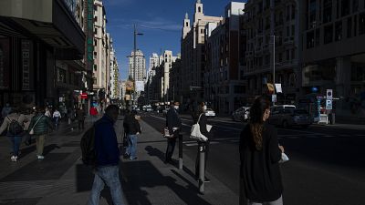 People walk through the Gran Via avenue in downtown Madrid, Spain, Monday, Oct. 5, 2020, during a partial lockdown