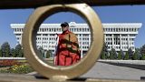 Мужчина с национальным флагом у здания правительства Киргизии