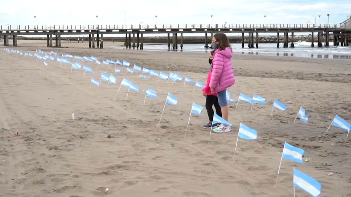 Dos niños argentinos observan las banderas clavadas en la playa Bristol