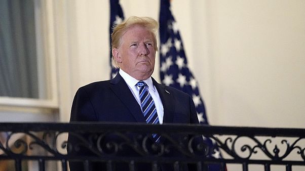 President Donald Trump stands on the balcony as returns to the White House on Monday, Oct. 5, 2020, after leaving hospital.