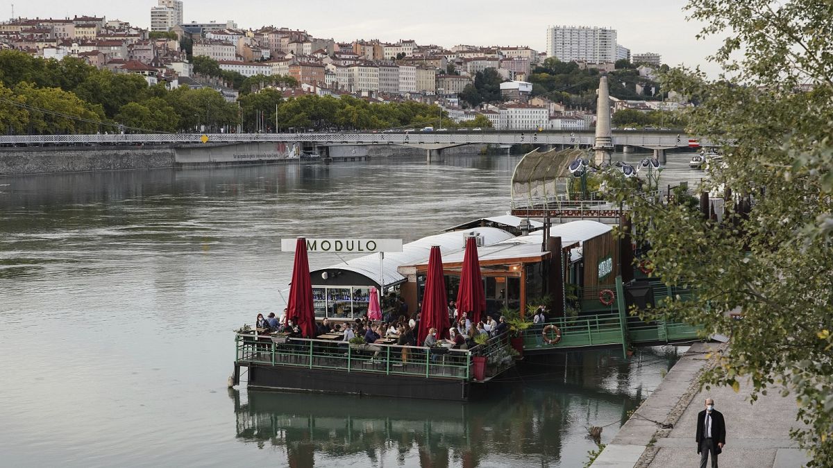 People enjoy a drink on a boat in the centre of Lyon, central France, Thursday, October 8, 2020. 