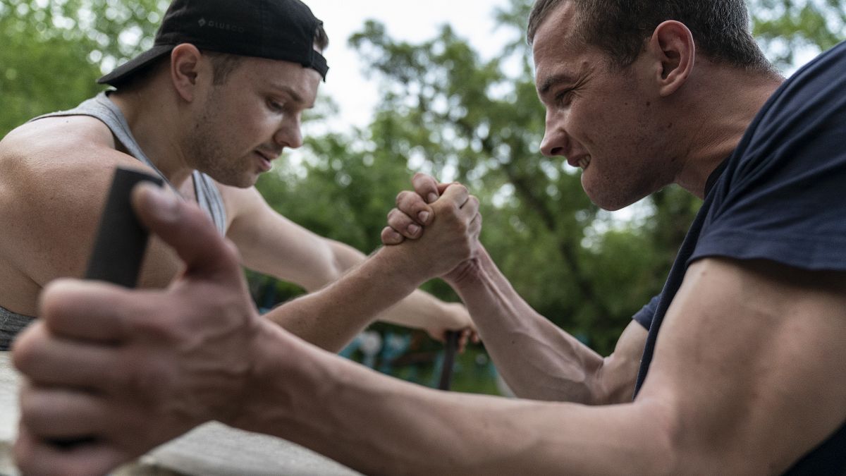 رجلان يتنافسان في مصارعة الأيدي على نهر دنيبرو في كييف، أوكرانيا.