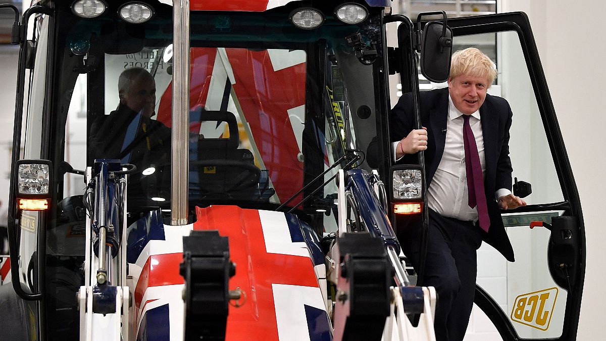 Boris Johnson exits the cab of a Union flag-themed JCB during an election campaign event at the JCB manufacturing plant in Uttoxeter, England, December 10, 2019. 