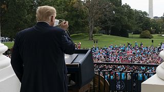 President Donald Trump removes his mask before speaking from the Blue Room Balcony of the White House to a crowd of supporters, Saturday, Oct. 10, 2020, in Washington.