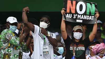 Ivorian MP Yasmina Ouegnin(R) holds a banner reading "No to third term" during a meeting against the candidacy for re-election of the incumbent president