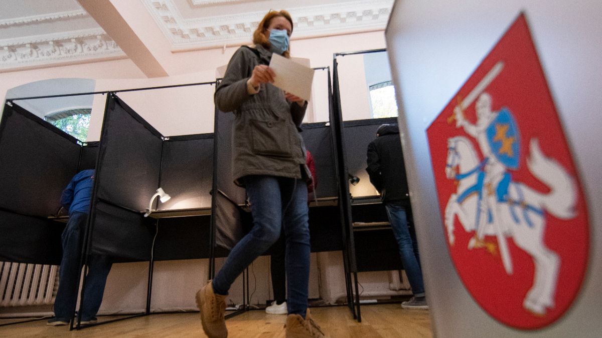 A voter walks past the Lithuanian coat of arms at a polling station during parliamentary elections in Vilnius, Lithuania, Sunday, Oct.11, 2020. 