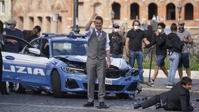 Actor Tom Cruise, center, waves to fans during a break in the shooting of the film Mission Impossible 7, in Rome