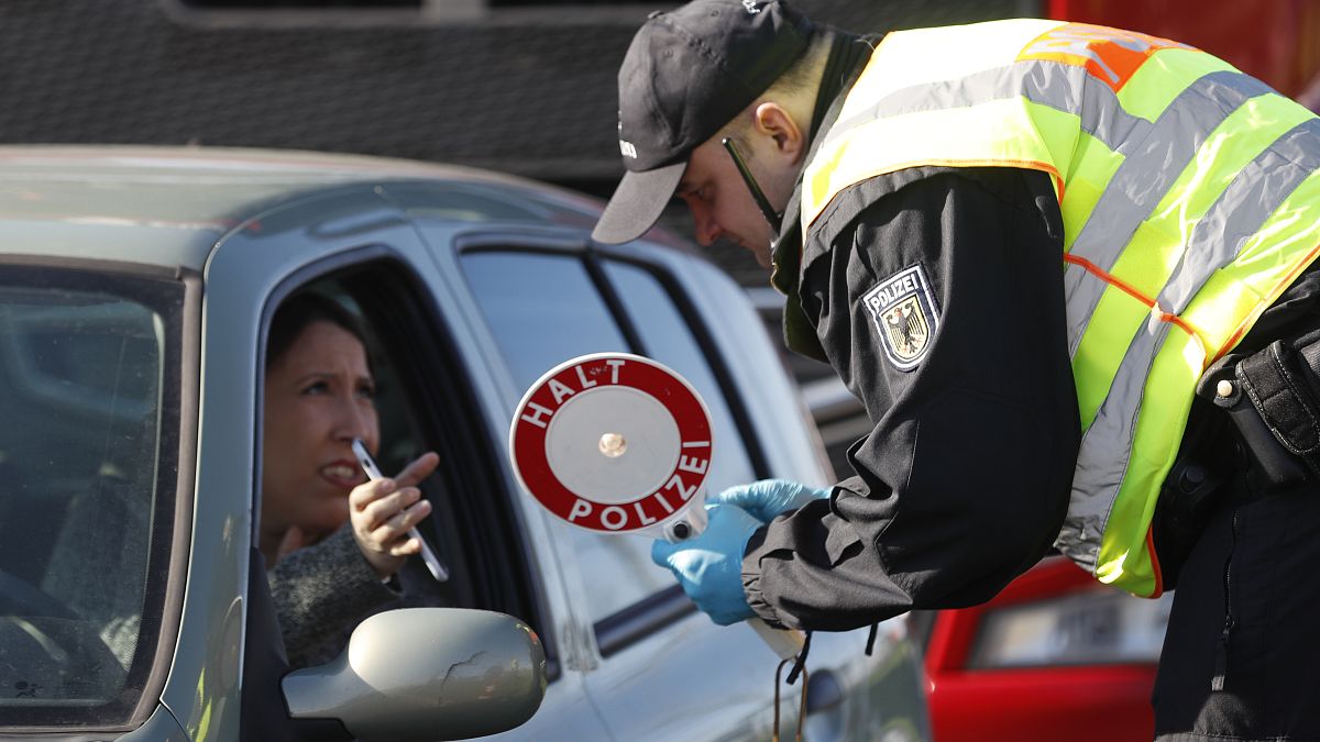 ضابط شرطة ألماني بفحص تصريح دخول امرأة إلى ألمانيا على الحدود الألمانية الفرنسية في كيل ، ألمانيا.