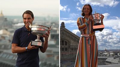 Iga Swiatek and Rafael Nadal pose for pictures on top of the Galeries Lafayette rooftop clutching their French Open trophy