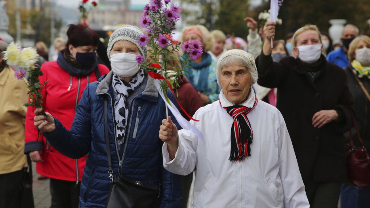 Elderly women hold flowers during an opposition rally to protest the official presidential election results in Minsk, Belarus, Monday, Oct. 12, 2020. 