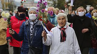 Elderly women hold flowers during an opposition rally to protest the official presidential election results in Minsk, Belarus, Monday, Oct. 12, 2020. 