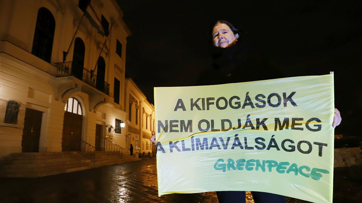 Dr. Bartholy Judit klímakutató tartja a Greenpeace tábláját Orbán Viktor hivatala előtt