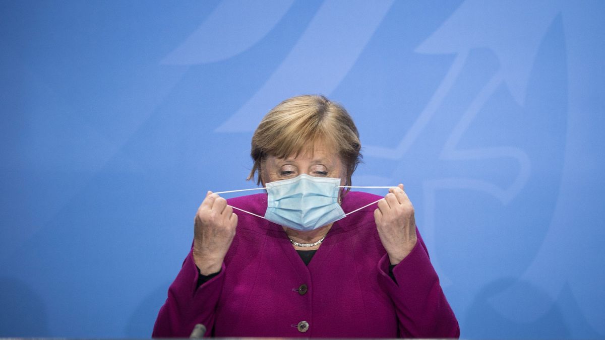 German Chancellor Angela Merkel holds her face mask as she arrives for a press conference after a meeting with the governors of the German states in Berlin, Oct. 14, 2020.