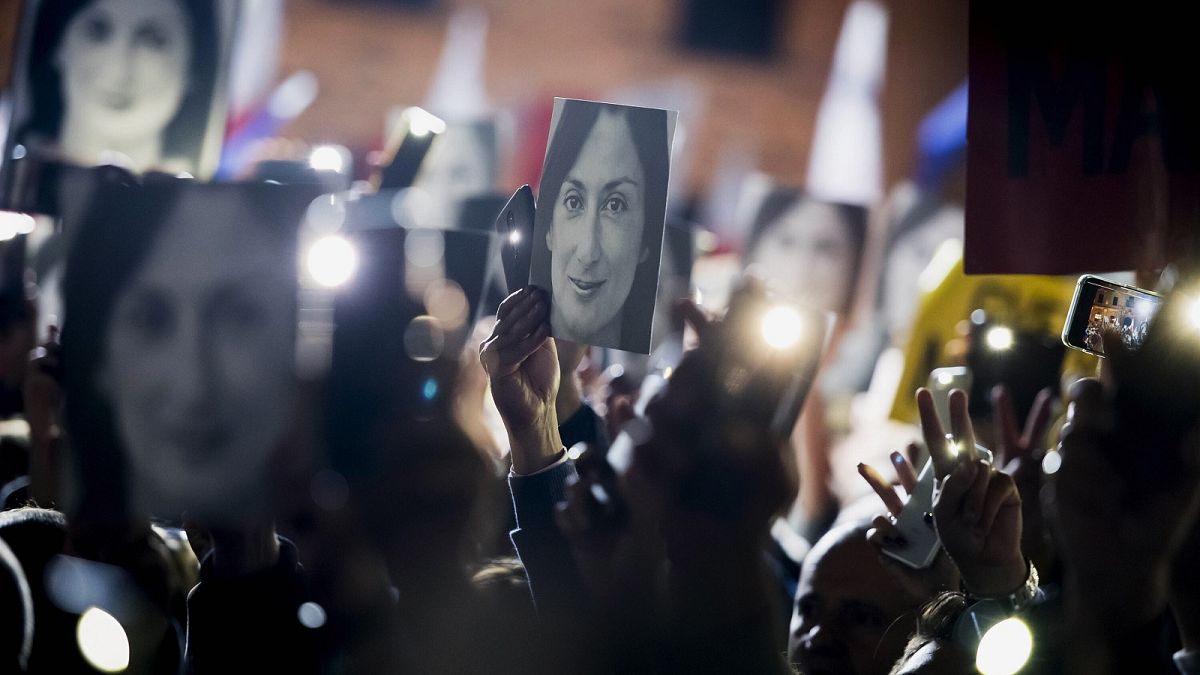 People hold pictures of slain journalist Daphne Caruana Galizia as they protest outside the office of the Maltese Prime Minister Joseph Muscat on Nov. 29, 2019.