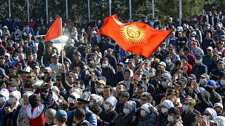 Protesters react waving Kyrgyz national flags as they wait in front of the government building in Bishkek, Kyrgyzstan.