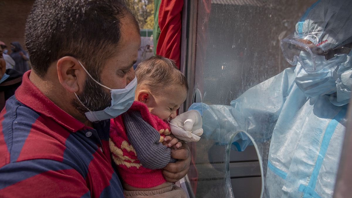 عامل صحي في كشمير يأخذ عينة مسحة أنف لطفل لاختبار كوفيد-19
