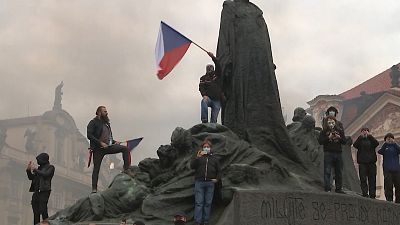 Men waving Czech flags from monument