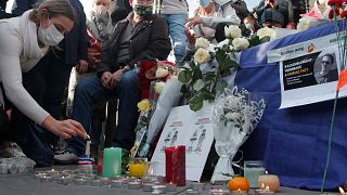 A woman lights a candle on Republique square during a demonstration in support of freedom of speech on Oct. 18, 2020 in Paris.