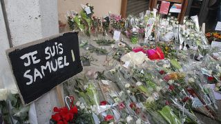 A poster reading "I am Samuel" and flowers lay outside the school where slain history teacher Samuel Paty was working, Saturday, Oct. 17, 2020.