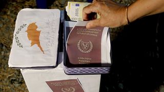 A demonstrator takes a mock copy of Cyprus passport during a demonstration against corruption in the capital Nicosia, Cyprus, Wednesday, Oct. 14 2020