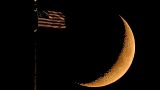 La Lune côtoie un drapeau américain, perché sur le toit de l'hôtel de ville de Kansas City - Missouri, Etats-Unis -, le 20 septembre 2020