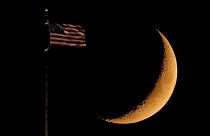 La Lune côtoie un drapeau américain, perché sur le toit de l'hôtel de ville de Kansas City - Missouri, Etats-Unis -, le 20 septembre 2020